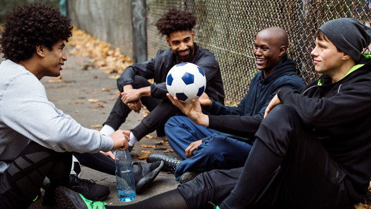 Male footballers having post-match discussion in inner-city environment 